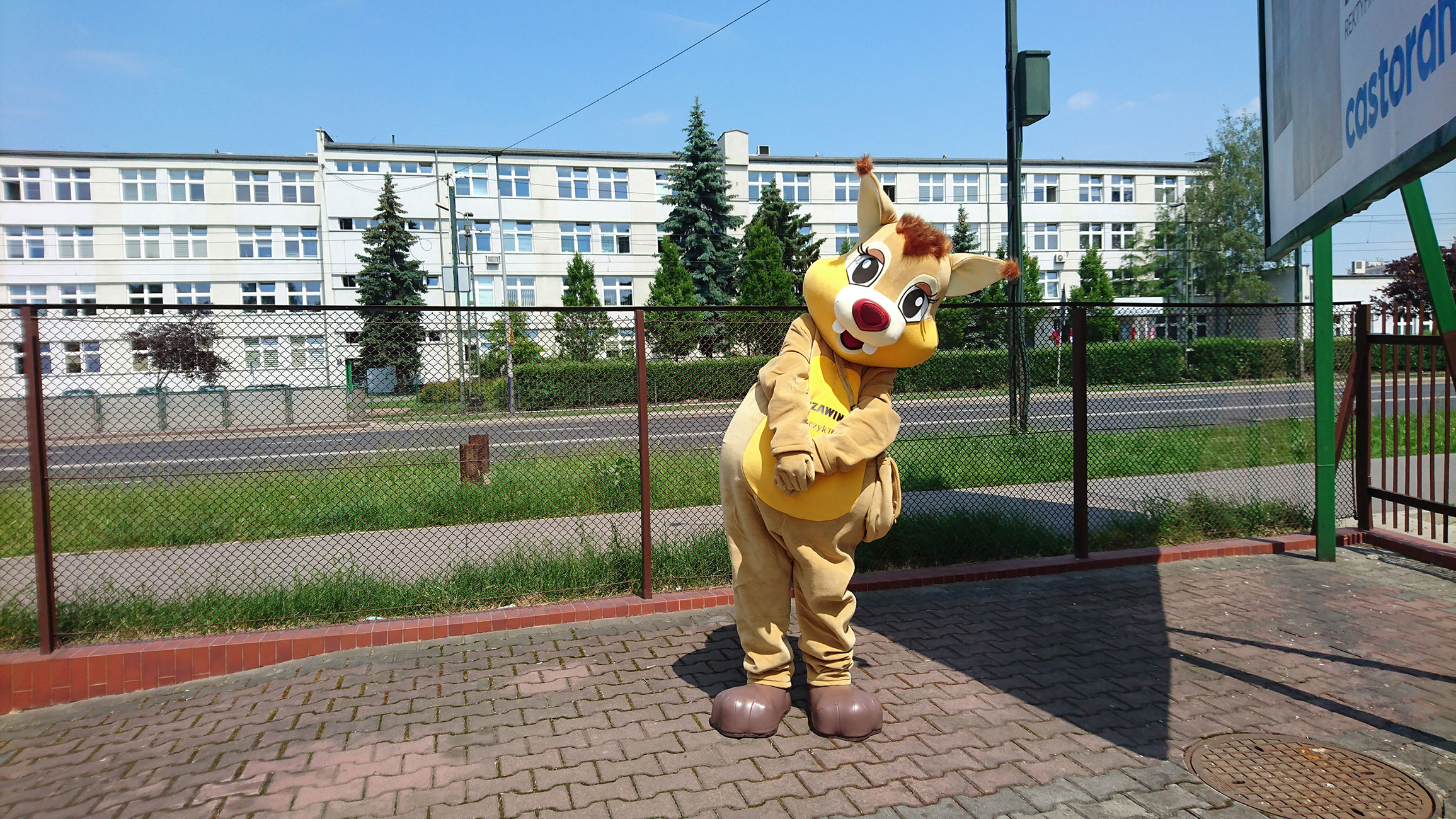 Na fotografii widnieje kostium reklamowy w postaci wiewiórki pozujący do zdjęcia obok siedziby firmy Elabika